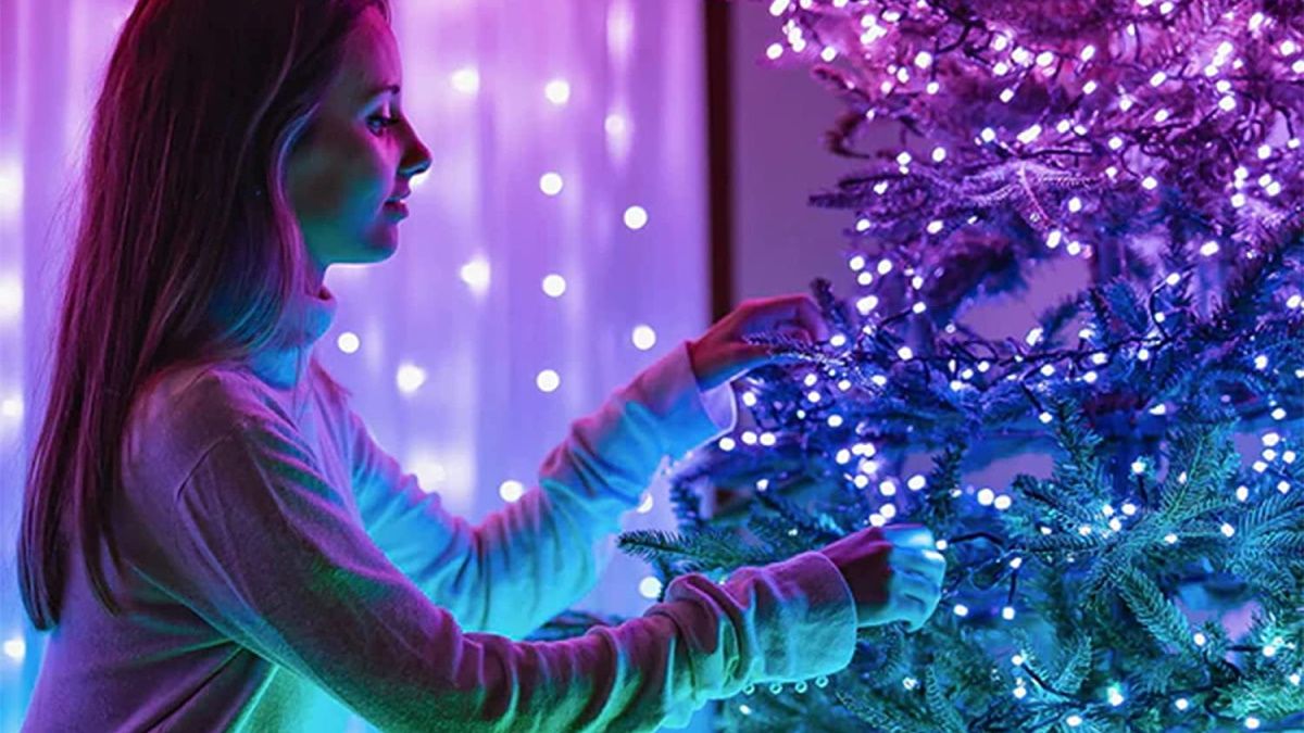 Pessoa amarrando luzes Twinkly na árvore de Natal