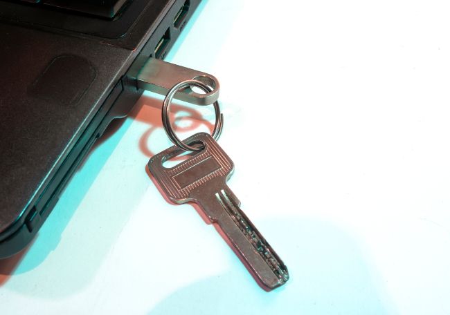 Uma unidade flash USB conectada a um laptop e anexada a um chaveiro com uma chave física.