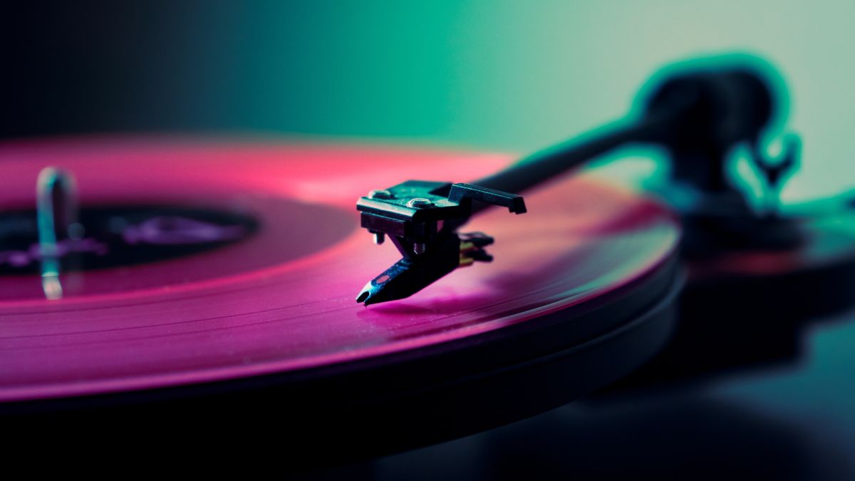 Close de um disco rosa sendo tocado em um toca-discos.