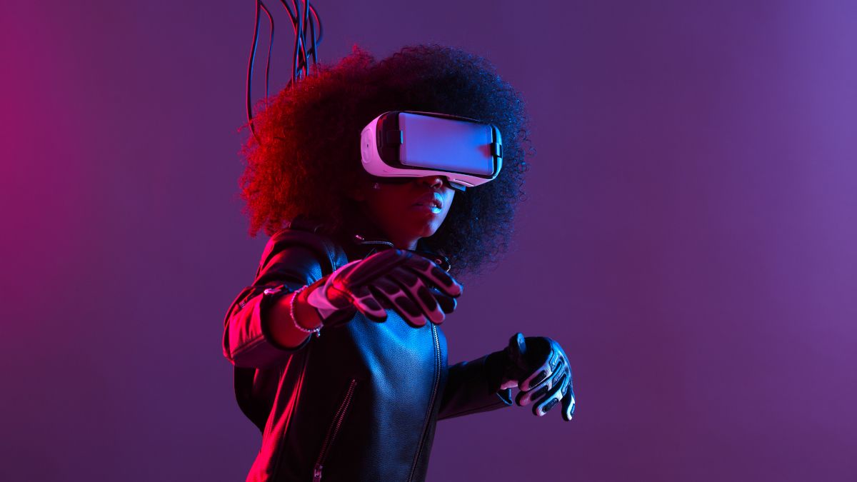 Mulher usando fone de ouvido de realidade virtual e luvas, com jaqueta conectada a fios.