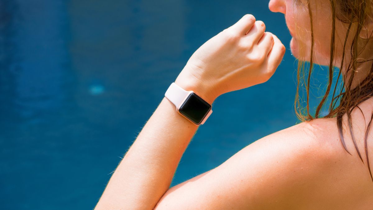 Um Apple Watch no pulso de uma mulher, com água azul ao fundo.