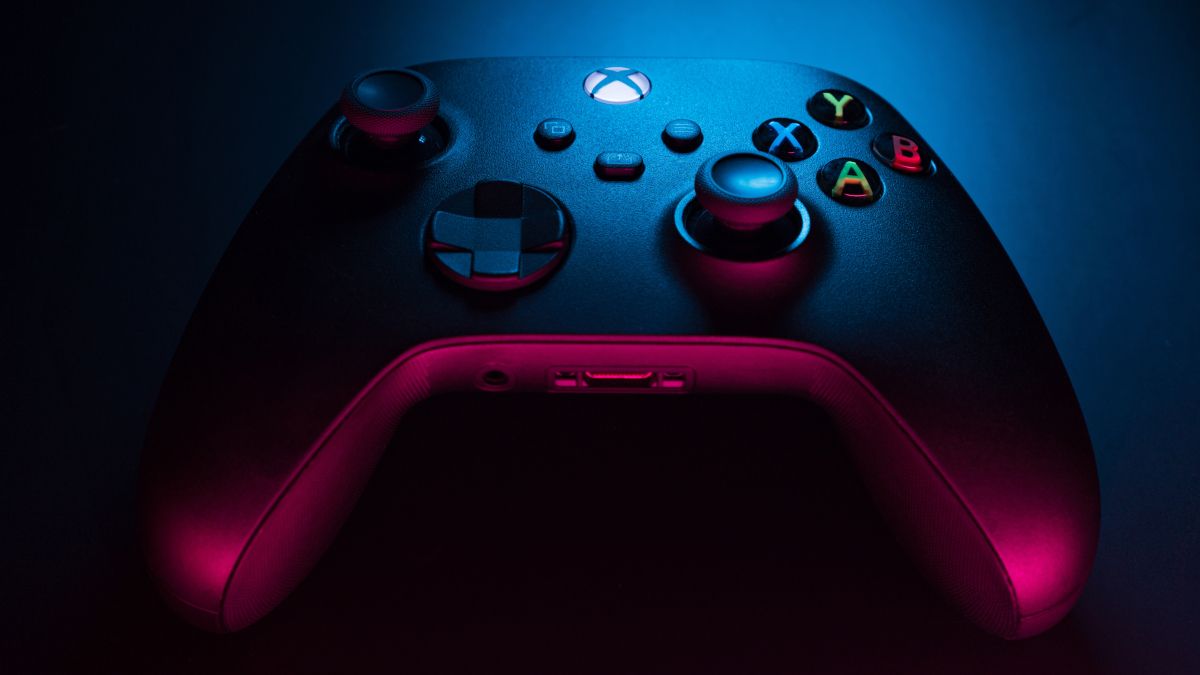Close de um controlador Xbox Series S em negro de fumo com iluminação azul e vermelha.